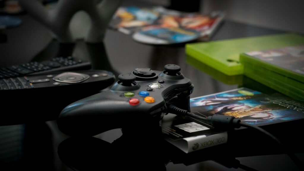 An xbox 360 controller lying next to several games.