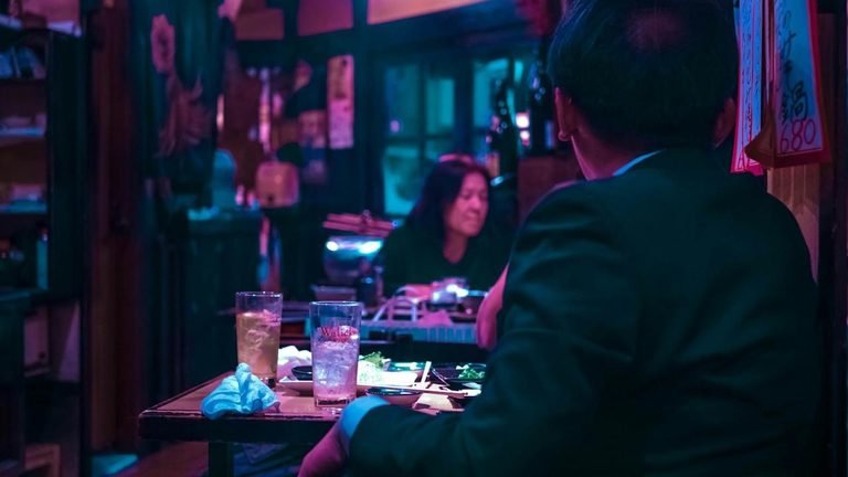 A man sitting alone at a table in a club.