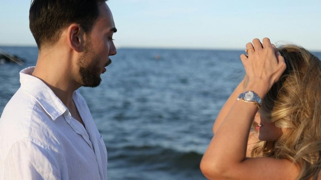 A man standing next to a woman on a beach.